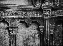 Photographie en noir et blanc montrant les arcatures aveugles du fond de l'abside, surmontées d'une frise décorative.