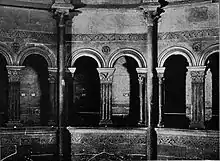 Photographie en noir et blanc montrant une galerie à six arcades.