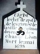 Boîte à crâne en forme de petite maison surmontée d'une croix avec une inscription dessus