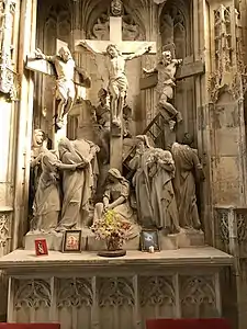 Grand groupe sculpté représentant trois hommes sur des croix. À leurs pieds, 7 personnages pleurant.