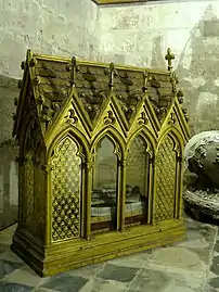 Reliquaire dorée prenant la forme d'une petite chapelle avec des fenêtres et contenant des ossements.