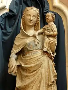 Dans une niche, partie supérieure d'une statue en pierre, peinte par endroits, d'une femme tenant un enfant avec son bras gauche. L'enfant présente la tête d'un adulte.