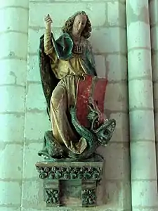 Statue peinte d'un jeune homme chevelu tenant une lance et un bouclier. À ses pieds, un dragon.