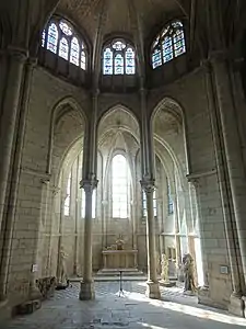 Chapelle contenant quelques statues, surmontée de trois vitraux décoratifs.