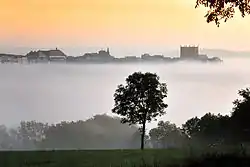 Ville haute de Saint-Flour émergeant au matin sur sa planèze de la brume noyant la ville basse