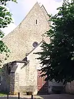 Derrière le toit de l'église, le bord du toit de son clocher en bâtière