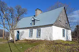 une maison blanche avec un toit en tôle bleu