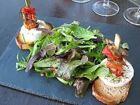 Du mesclun encadré de deux toasts au chèvre chaud et légumes