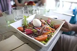 Un ramequin blanc et carré de salade niçoise