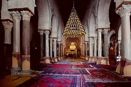 Photographie de la nef centrale de la salle de prière. Plus large et plus haute que les seize autres nefs, elle mène au mihrab. Elle est bordée, de part et d'autre, d'une double ligne d'arcades à colonnes géminées.