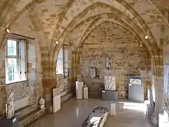 Salle voûtée en pierre avec des sculptures exposées.