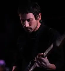 Vue de face de Sam Roberts sur scène, tenant sa guitare.