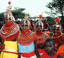 Photographie d'un groupe de jeunes filles portant de nombreux colliers et des vêtements de couleurs vives