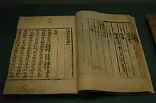 Livre ouvert sur un présentoir. Le texte y est rédigé en caractères chinois.