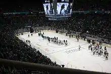 Photogaphie d'une patinoire de hockey sur glace depuis les tribunes avec des joueurs sur la glae.