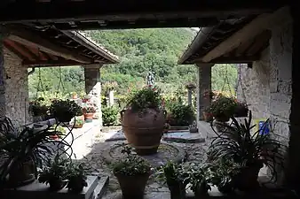 Cour végétalisée encadrée de colonnes et ouvrant sur un paysage de moyenne montagne.