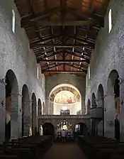 Nef d'église sous charpente de bois, à bas-côté romans.