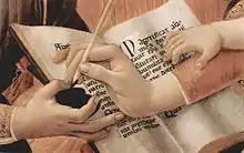 Détail du tableau de Botticelli : une main porteuse d'un encrier (celle d'un des personnages entourant la Vierge), celle de la Vierge y trempe la plume tandis qu'une troisième main plus petite (celle de l'Enfant-Jésus) repose sur l'avant-bras de Marie : elle écrit le Magnificat en latin sur la page d'un cahier blanc. et elle va faire suivre le mot Quia (déjà calligraphié,par lequel commence le troisième verset), des mots qui achèvent le verset : « [Quia] fecit mihi magna qui potens est » (« Car il a fait pour moi de grandes choses celui qui est puissant »).