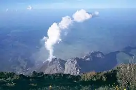 Le dôme de lave fumant du Santiaguito vu depuis le sommet du Santa María, en arrière-plan la plaine côtière bordant l'océan Pacifique.