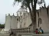 Vue de la façade latérale du sanctuaire de Jésus Nazareno de Atotonilco. Deux femmes sont assises sous un arbre, sur le côté droit de la photographie.