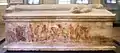 Vue d'un long côté du sarcophage avec sur la partie inférieure une peinture avec des personnages