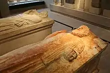 Vue d'une sarcophage dont le couverte sculpté représente un personnage.