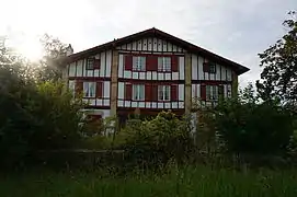 Vue d'une maison à deux étages aux pans de bois rouge.
