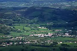 Vue aérienne d’un village dominé par des collines.