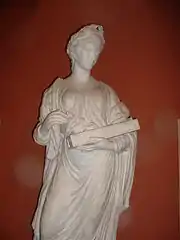 Statue grecque en pied d'une femme couronnée de lauriers, tunique drapée, un instrument en main (environ 50 cm).