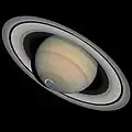 Vue en contreplongée montrant la face sud des anneaux et un cercle bleu au sud de Saturne.