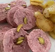 Saucisson chaud truffé aux pistaches et pommes de terre sautées.