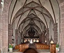 photographie en couleur montrant l’intérieur d’une église couvert par des voûtes retombant sur des piliers en grès rose