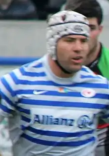 Photographie d'un homme en tenue de rugby, avec un casque de rugby.