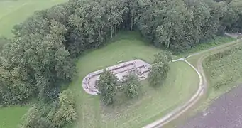 Photographie en couleurs et en hauteur des ruines d'un bâtiment entouré par des massifs d'arbres