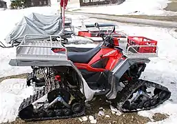 Véhicule tout-terrain (VTT) dont les roues sont remplacées par des chenilles.