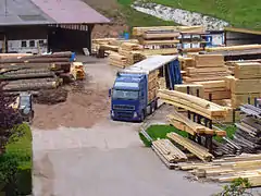 À gauche, parc à grumes. À droite, planches en attente de livraison.