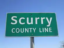 Panneau de signalisation routière, vert sur fond blanc, avec inscription Scurry county line.