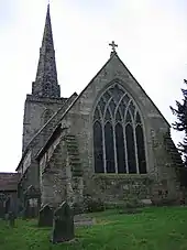 Photo d'une église en pierre grise avec une tour munie d'une flèche