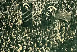 Photographie montrant une foule de personnes portant des banderoles avec des inscriptions en arménien et en turc ottoman.
