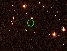 Sur un fond d'étoiles rouges, un cercle vert identifie un des petits points rouges.