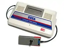 Photo d'une console blanche, rouge et bleu, à laquelle est branché un joystick gris.