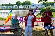 Ségolène Amiot a un de ses meetings en train d'applaudir entourée de deux militants.