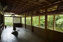 Chambre avec plancher en bois ouvert sur deux côtés. Il y a une petite statue placée dans le centre de la pièce.