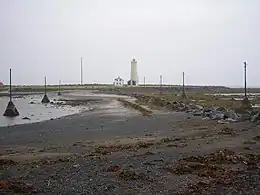 Vue de Grótta et de son phare à marée basse depuis la péninsule de Seltjarnarnes.