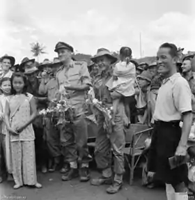 Photo en noir et blanc d'un général en uniforme posant avec des civils.