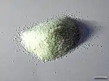 Un tas de grains de semoule, aussi appelée schemoul (spécialité juive, couleur blanc jaune, chaque grain faisant moins de 1 millimètre, sur un fond gris.