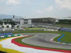Piste goudronée de Formule 1 au niveau d'une chicane, avec une tribune en arrière plan