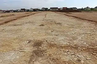 Vue d'une bande de terrain décapée superficiellement avant une fouille archéologique.