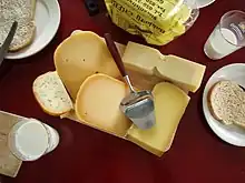 photo montrant un plateau de fromages variés, accompagné de pain et de lait.