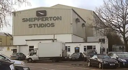 Photographie de la façade des studios vue depuis un parking. C'est un bâtiment bas, clair, portant le nom du studio en grandes lettres grises.